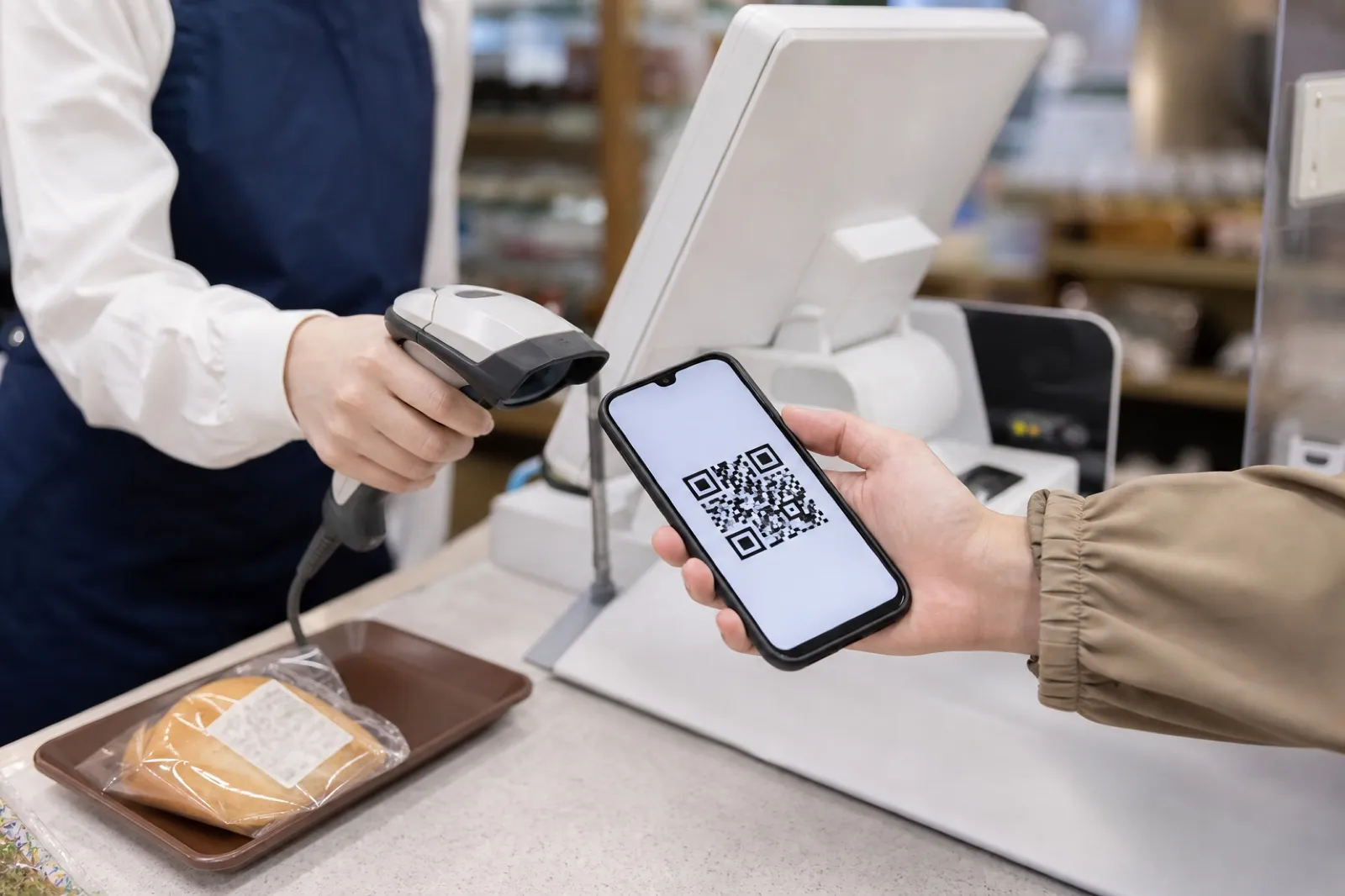 スマートフォンのQRコードで支払う手元（円はすでにデジタルとして動いているイメージ）