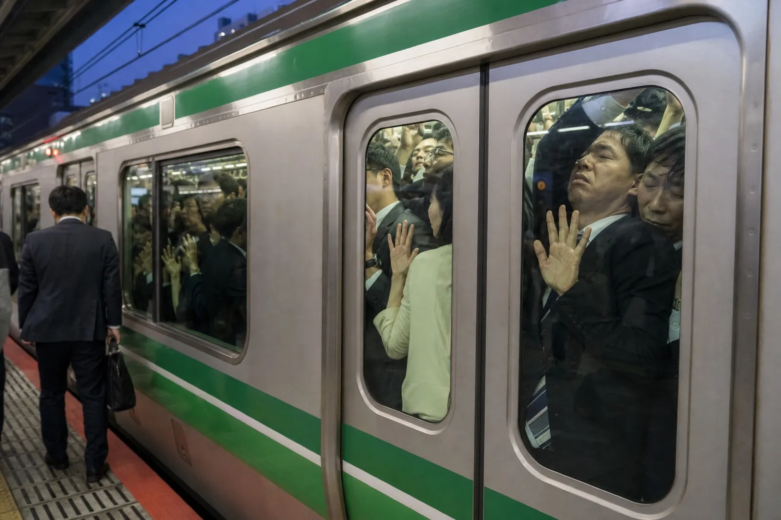 ドアに押し付けられた満員電車の乗客の写真